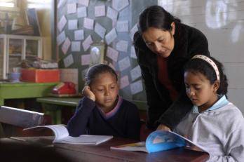 A teacher helps two girls in the classroom in Honduras.
